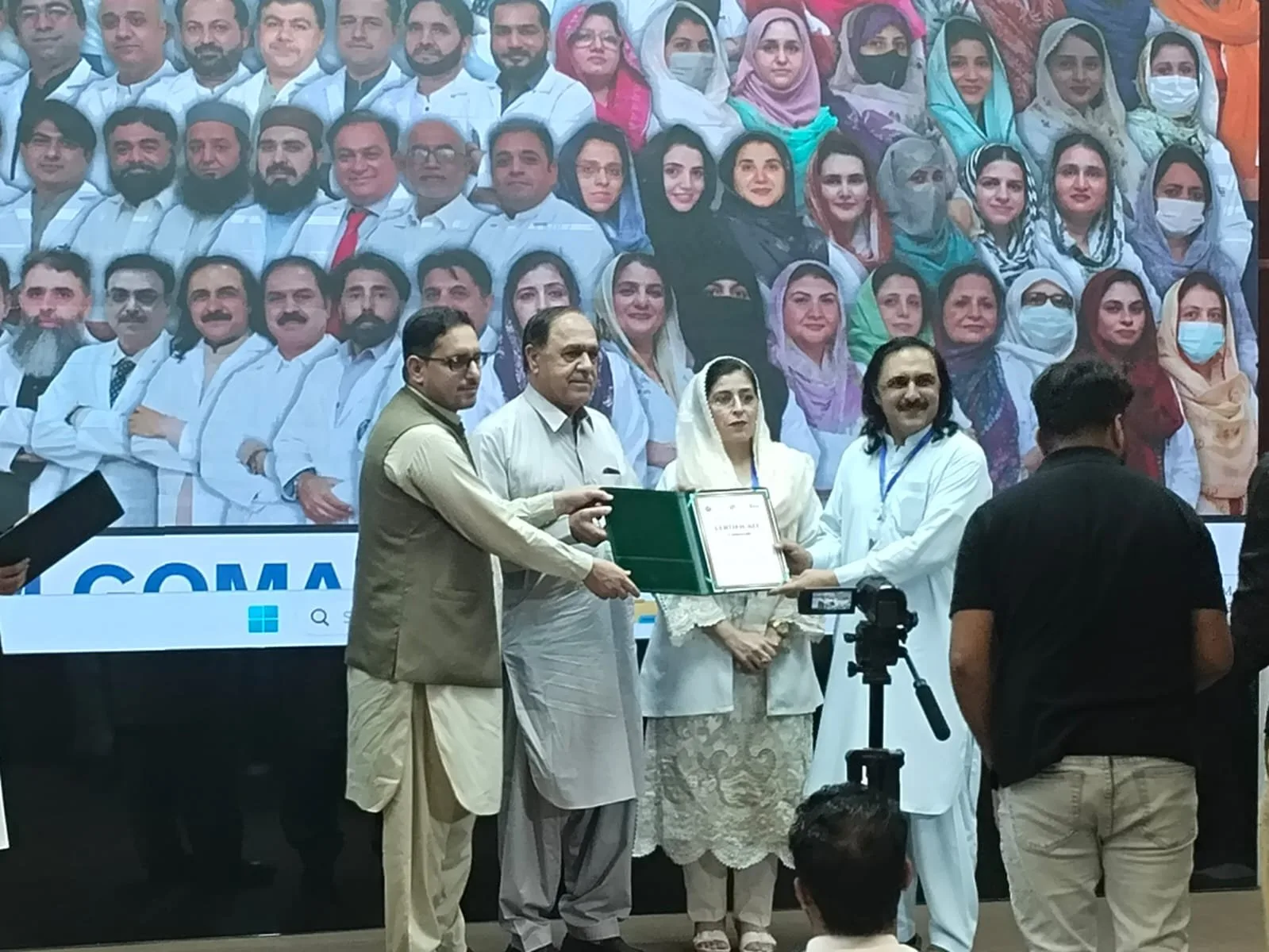 Delegates and faculty gathered for a group photograph at Gomal Medical College with the award certificate